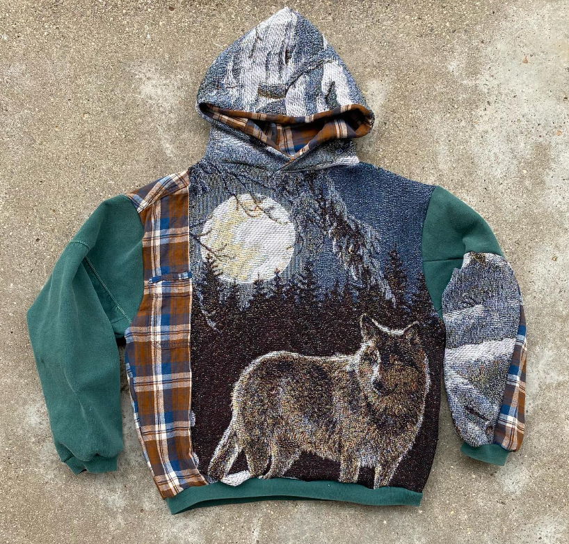 a photograph of a garment by jackswes on instagram, which is a hoodie that is stitched together from three separate garments - a green hoodie, a flannel jacket and a woven blanket with the image of a wolf.